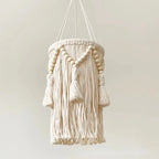  abat-jour nordique en macramé avec des perles et des franges décoratives suspendu au plafond, éclairé.