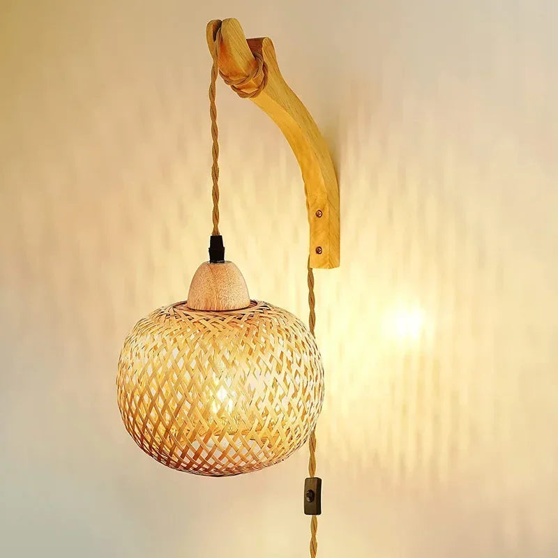 Applique murale en rotin avec lampe suspendue et cordon visible, éclairage chaleureux.