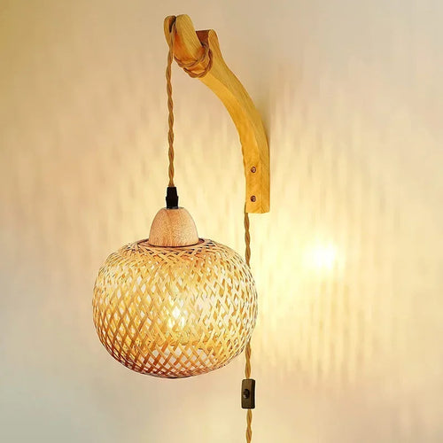 Applique murale en rotin avec lampe suspendue et cordon visible, éclairage chaleureux.
