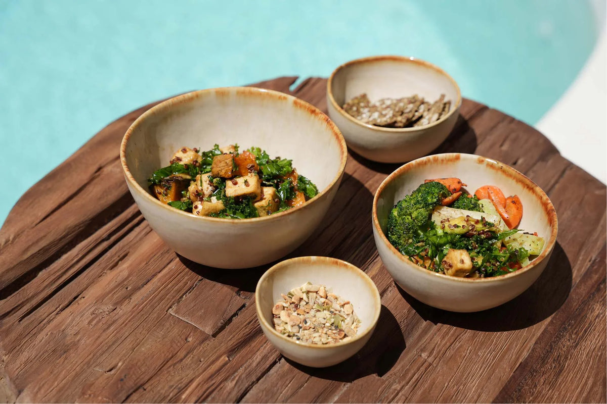 Bol en céramique artisanale beige avec salades colorées de légumes et tofu