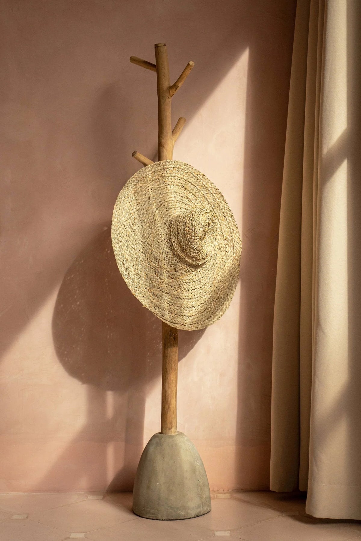 Chapeau de paille en jacinthe d’eau naturel à bord XXL souple sur porte-manteau en bois rustique
