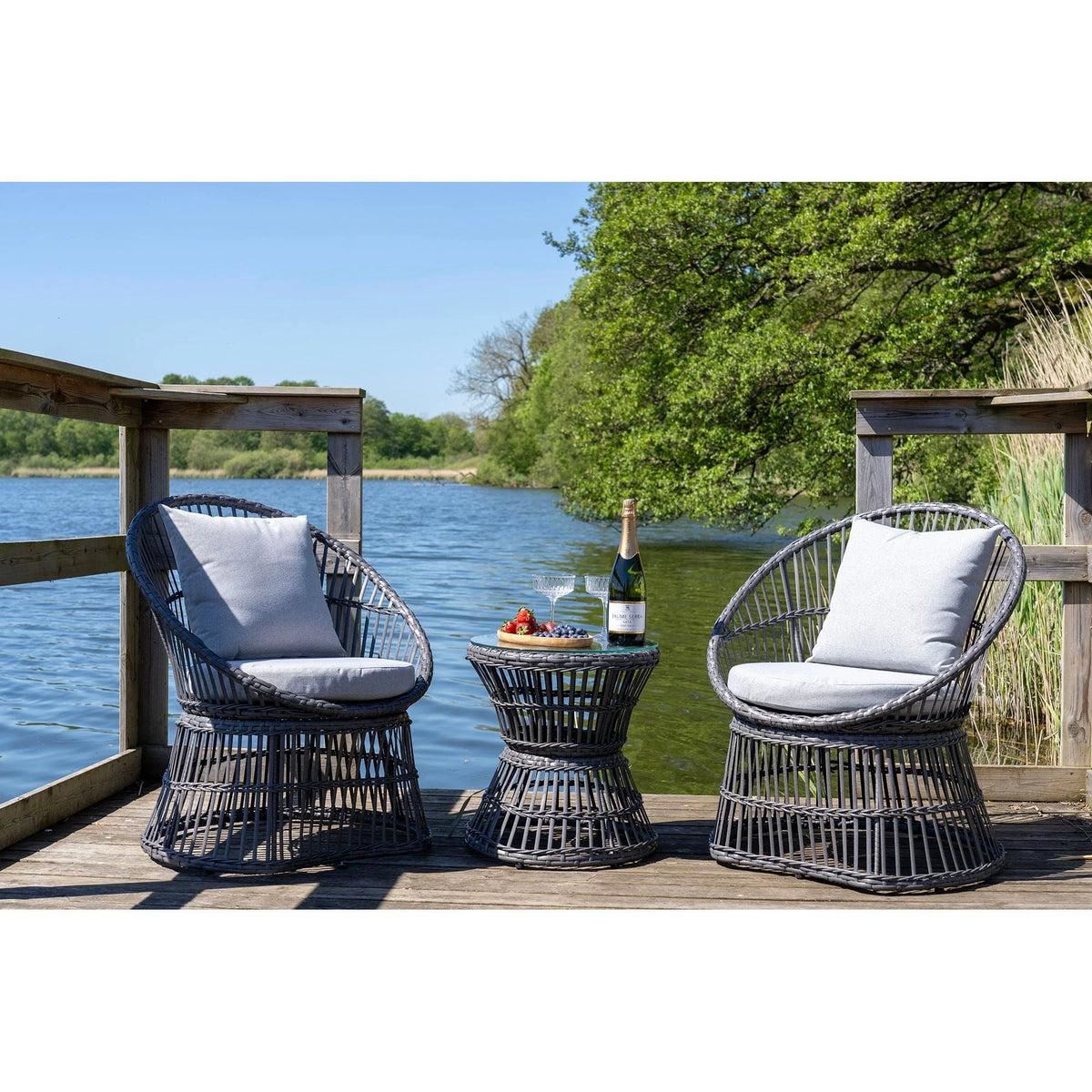 Ensemble lounge en rotin gris foncé avec coussins gris clair et table ronde