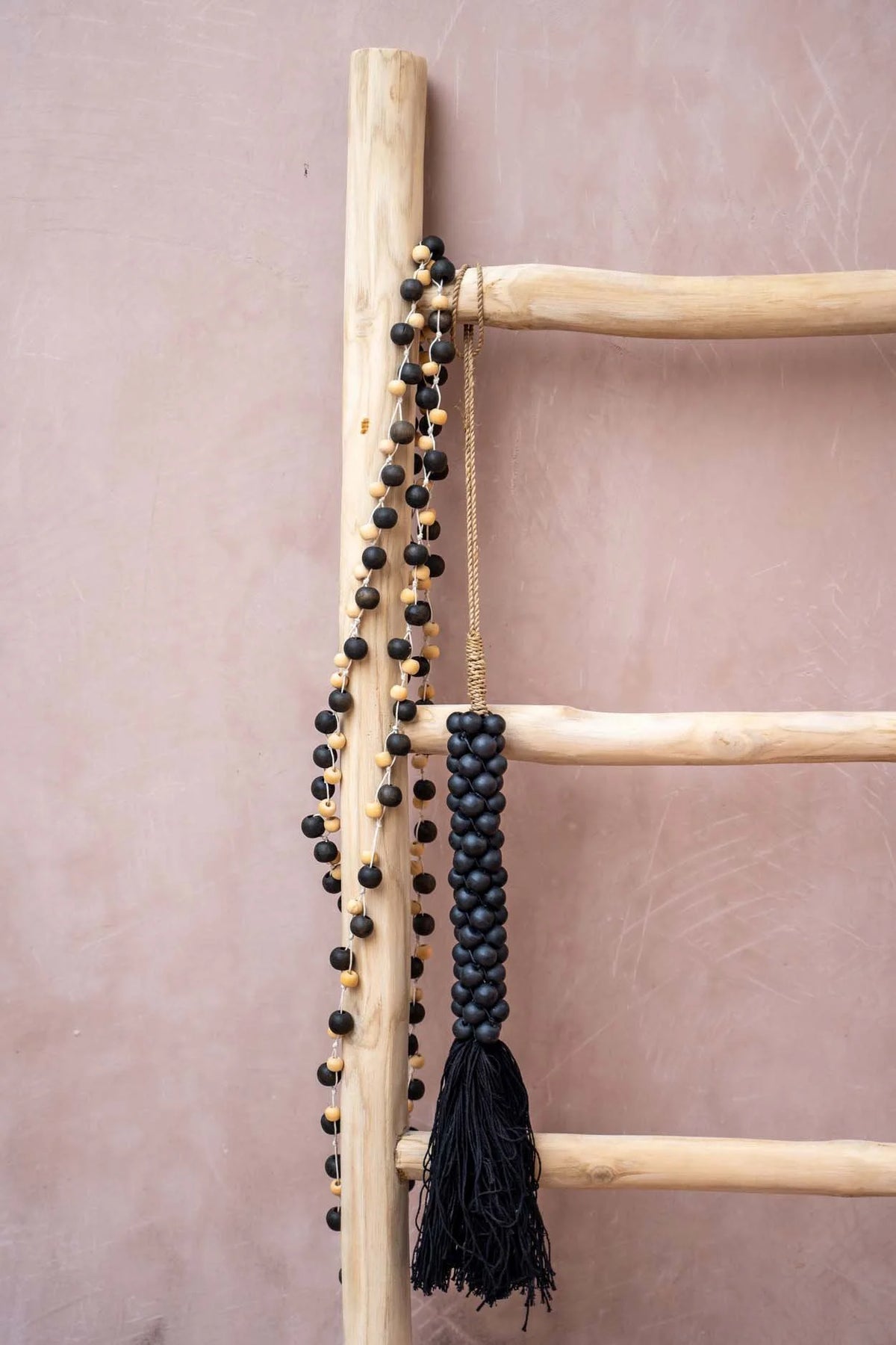 Échelle en bois avec collier de perles noires et gland torsadé