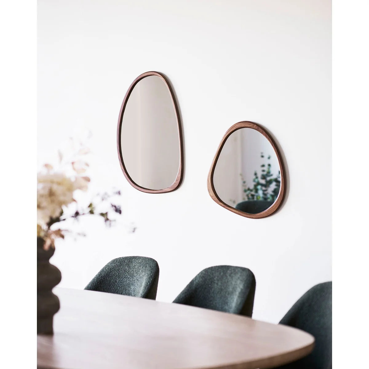 Deux miroirs ovales aux cadres en bois naturel chaud sur mur blanc