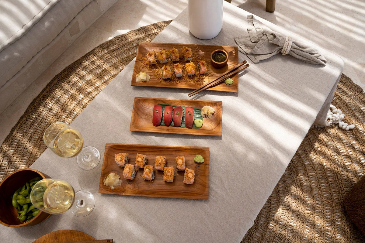 Platters en bois avec sushi, edamame et vin blanc sur nappe en lin beige