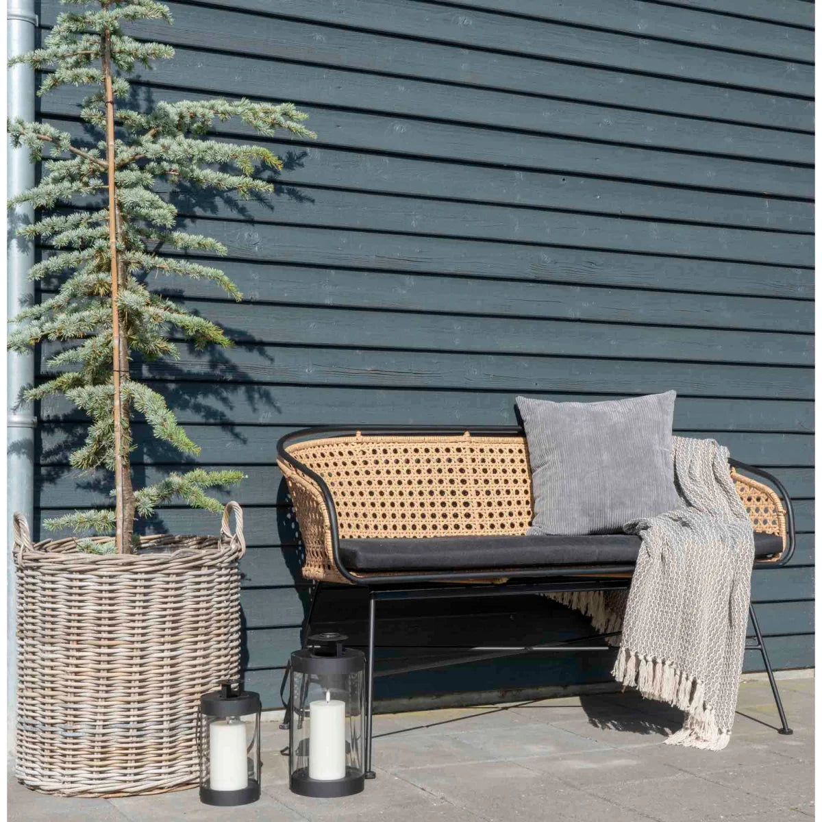 Banc en rotin tressé avec cadre métal noir et coussin foncé