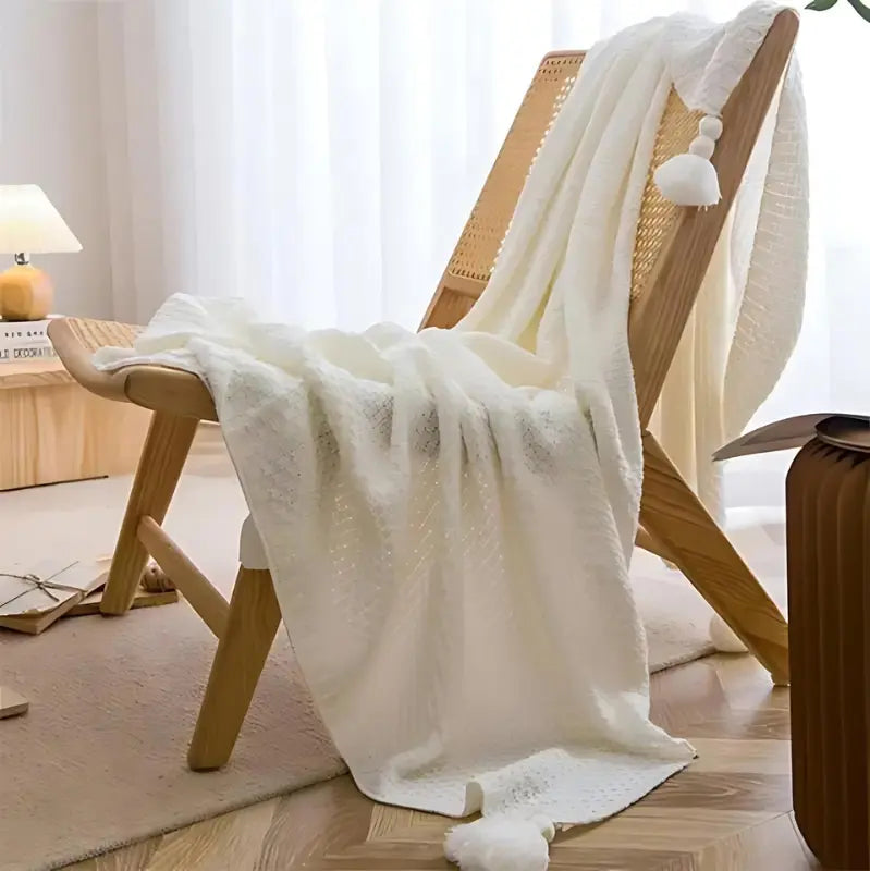 Plaid blanc en maille gaufrée posé sur une chaise en bois