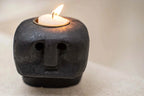 Bougeoir visage en grès noir sculpté avec bougie tea light allumée