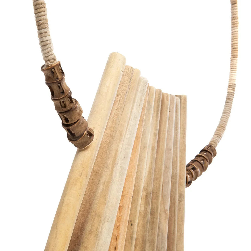 Flûte de pan en bois clair avec perles décoratives sur socle en bois naturel