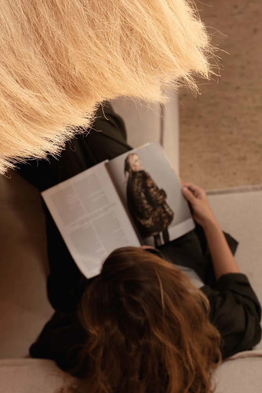Personne blonde lit magazine avec personne en manteau sombre sous suspension cloche paille frangée Ø60 cm