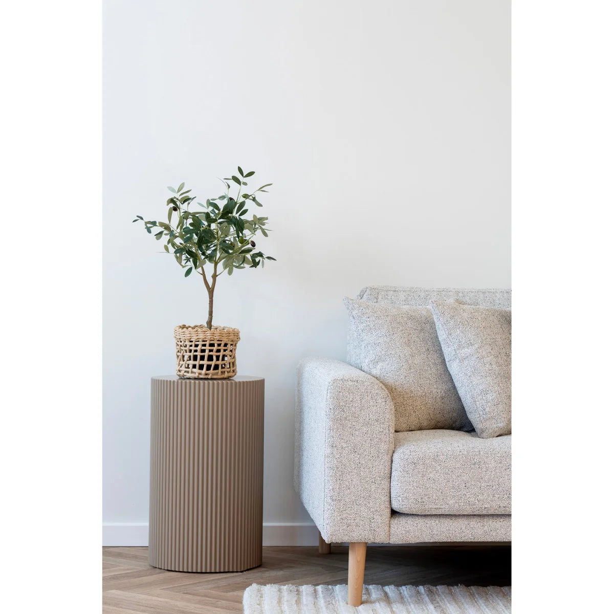 Petit olivier dans panier osier sur table ronde en MDF gris beige ø30x50 cm