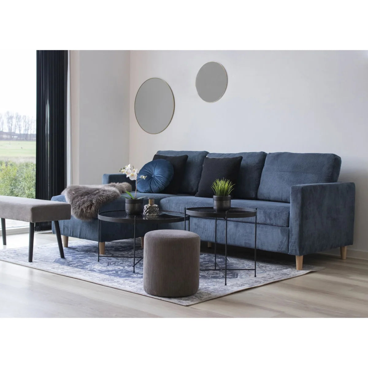Canapé sectionnel en velours côtelé bleu avec coussins noirs et couverture grise en fourrure texturée