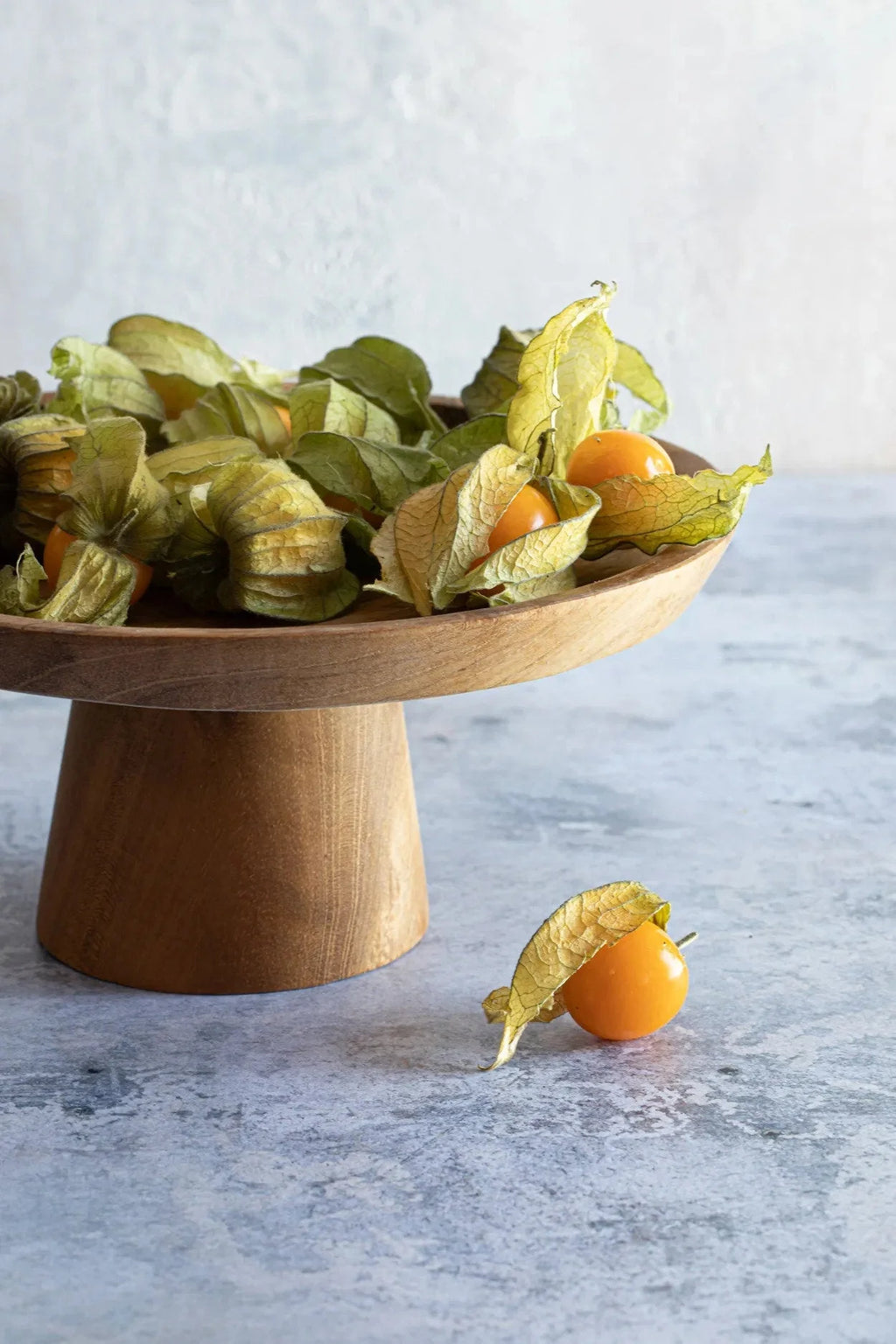 Plateau à gâteau en teck avec baies dorées et husks sur la table