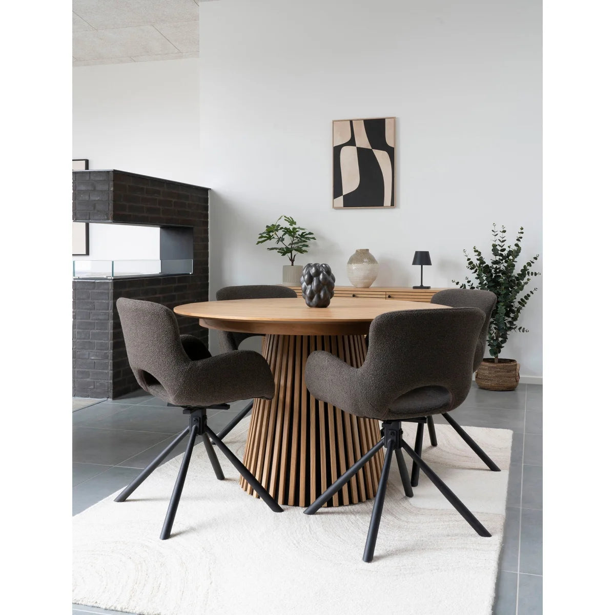 Table ronde en bois avec base ajourée et chaises grises rembourrées