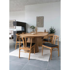 Table à manger en bois clair avec base cannelée, chaises tapissées noires